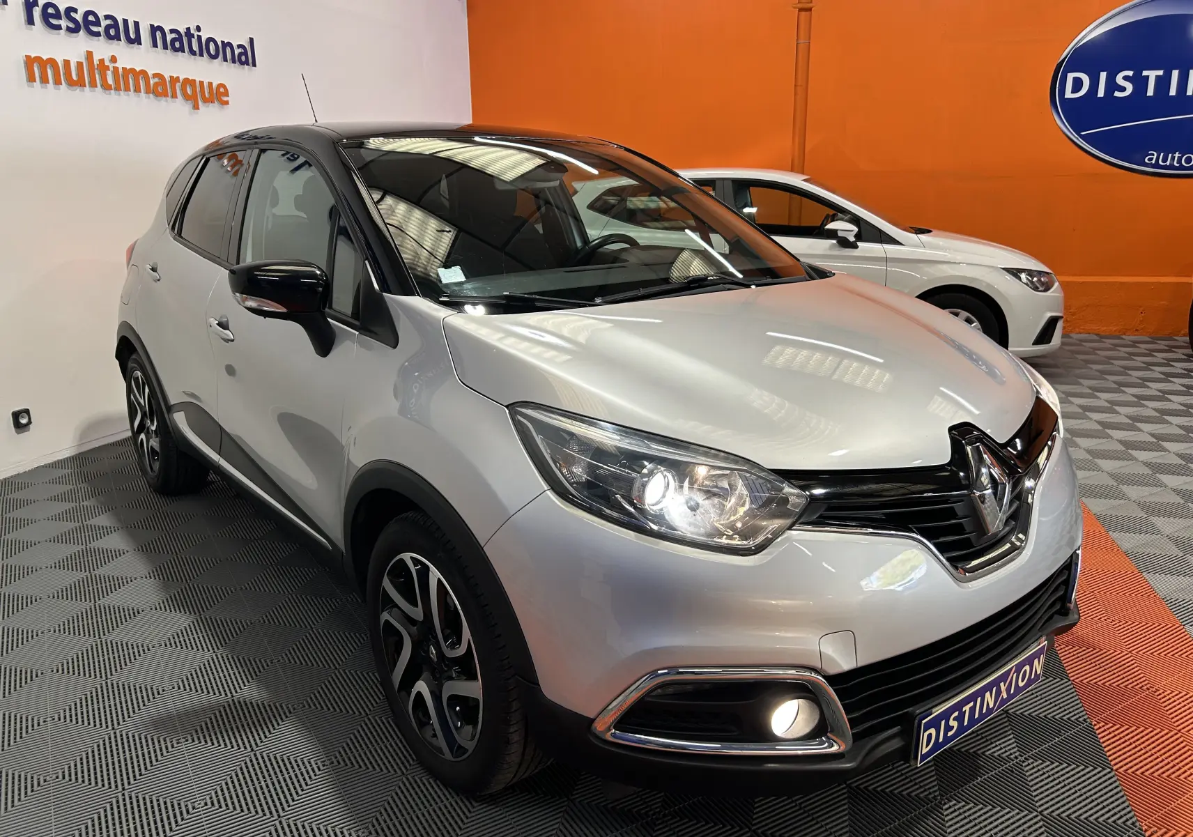 Renault Captur gris en 3/4 avant droit avec phares allumés et jantes alliage noires et argentées.