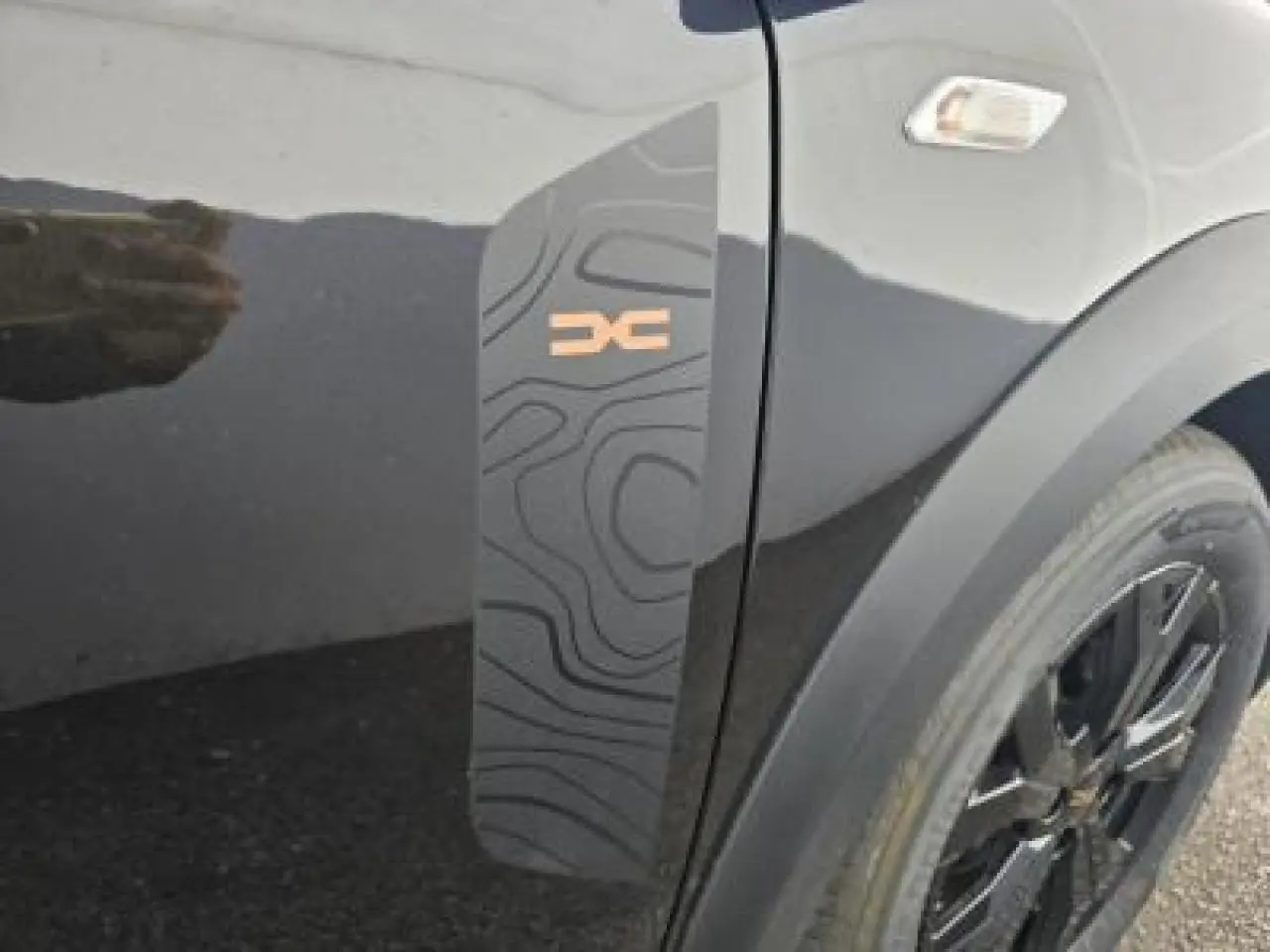 Détail du sticker topographique noir avec logo Stepway brun sur la porte côté avant droit d'une Dacia Sandero III Stepway noir nacré.