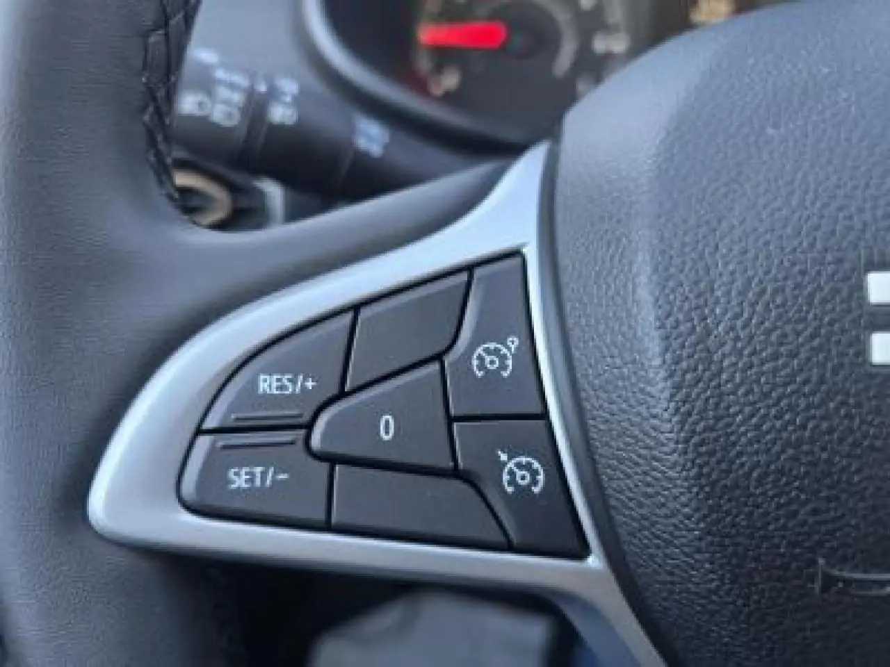 Gros plan sur les commandes du régulateur de vitesse au volant noir du Dacia Sandero III Stepway 2025.