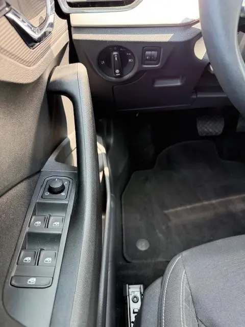 Détail intérieur côté conducteur du Skoda Kamiq noir 2024, montrant les commandes des vitres et l'interrupteur des phares.