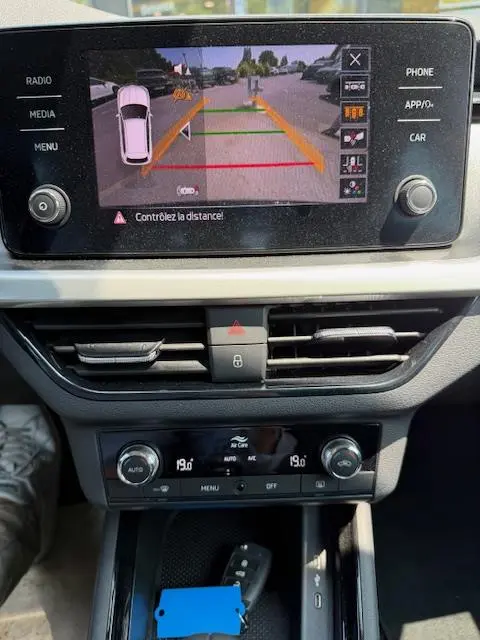Vue rapprochée de l'écran tactile central affichant la caméra de recul du Skoda Kamiq noir 2024 avec commandes climatisation en dessous.