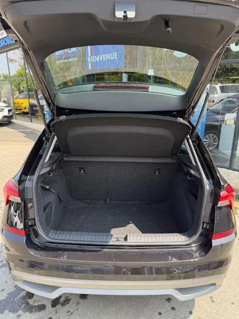 Vue arrière du coffre ouvert d'un Skoda Kamiq noir 2024, montrant l'espace de chargement et la tablette de séparation.