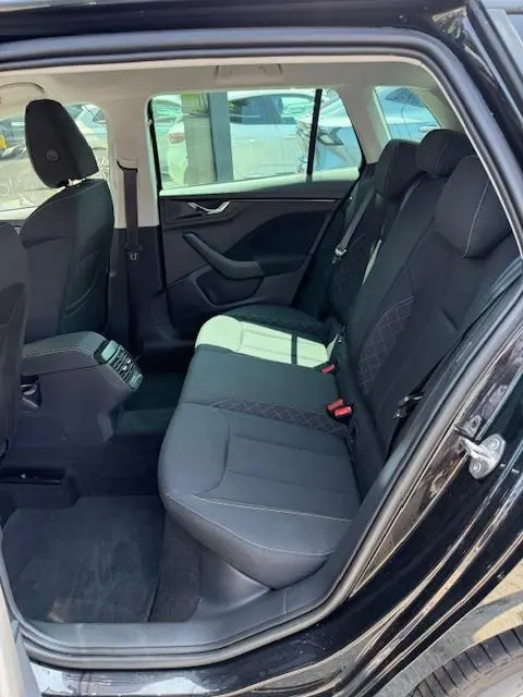 Vue intérieure côté droit de la banquette arrière noire du Skoda Kamiq 2024 avec finitions tissu et ceinture de sécurité rouge.