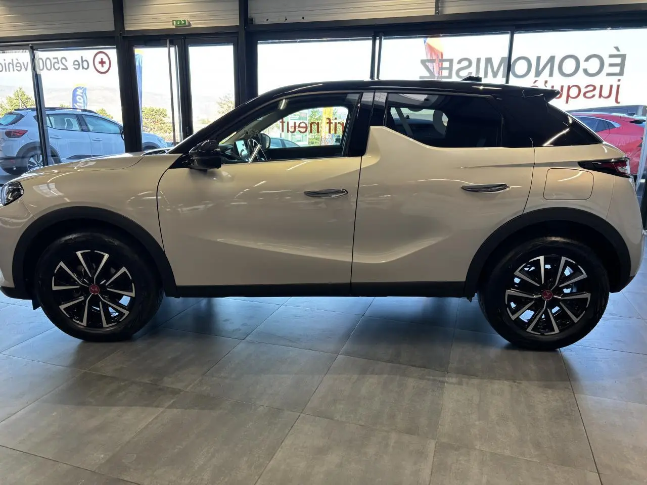 Vue de profil côté gauche du DS3 Crossback 2024 en couleur Crystal Pearl avec toit noir et jantes noires distinctives.