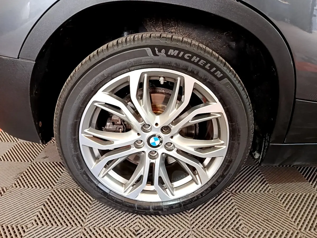 Gros plan sur la roue avant droite avec jante alliage argentée du BMW X2 hybride rechargeable couleur gris foncé.