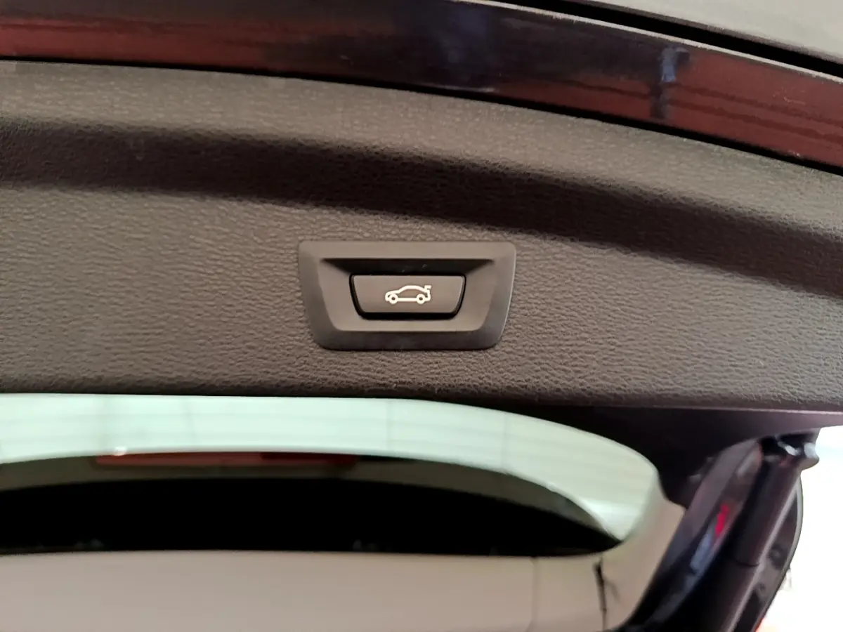 Bouton d'ouverture électrique du coffre sur la partie intérieure du hayon d'un BMW X2 hybride rechargeable, couleur sombre.