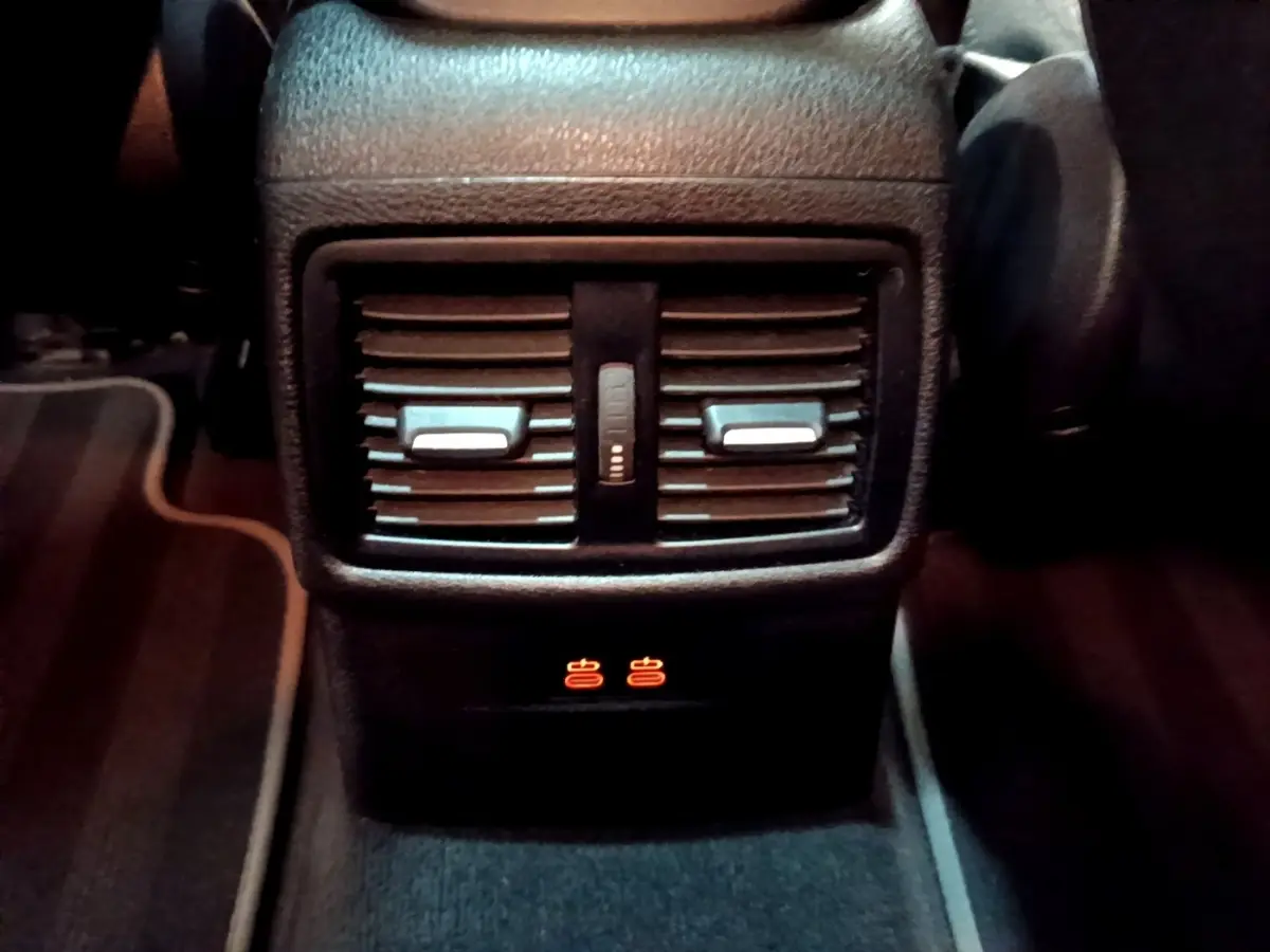 Gros plan sur la console centrale arrière noire du BMW X2 xDrive25e avec aérateurs et voyants chauffants allumés.