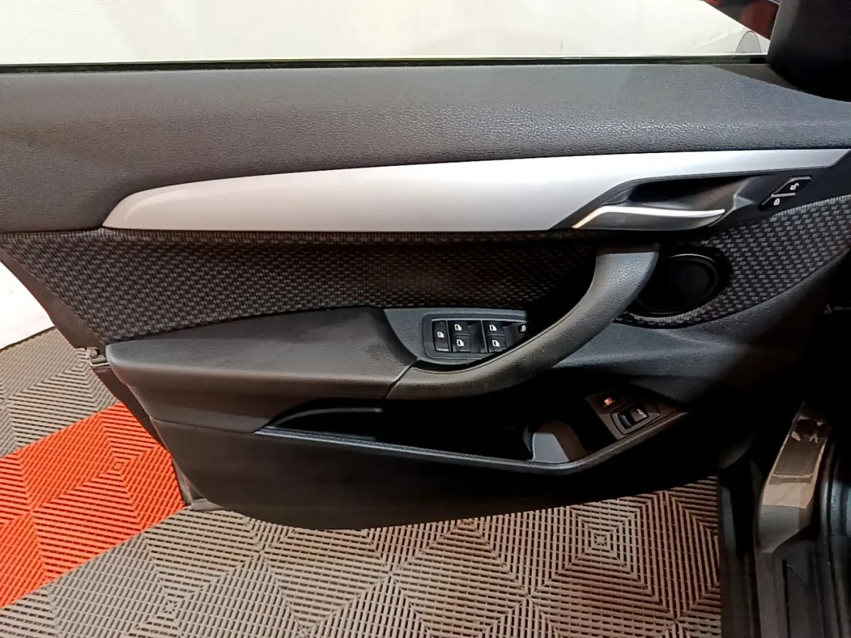 Vue rapprochée de la porte avant gauche de la BMW X2 hybride rechargeable, avec garniture noire et insert gris métallique.