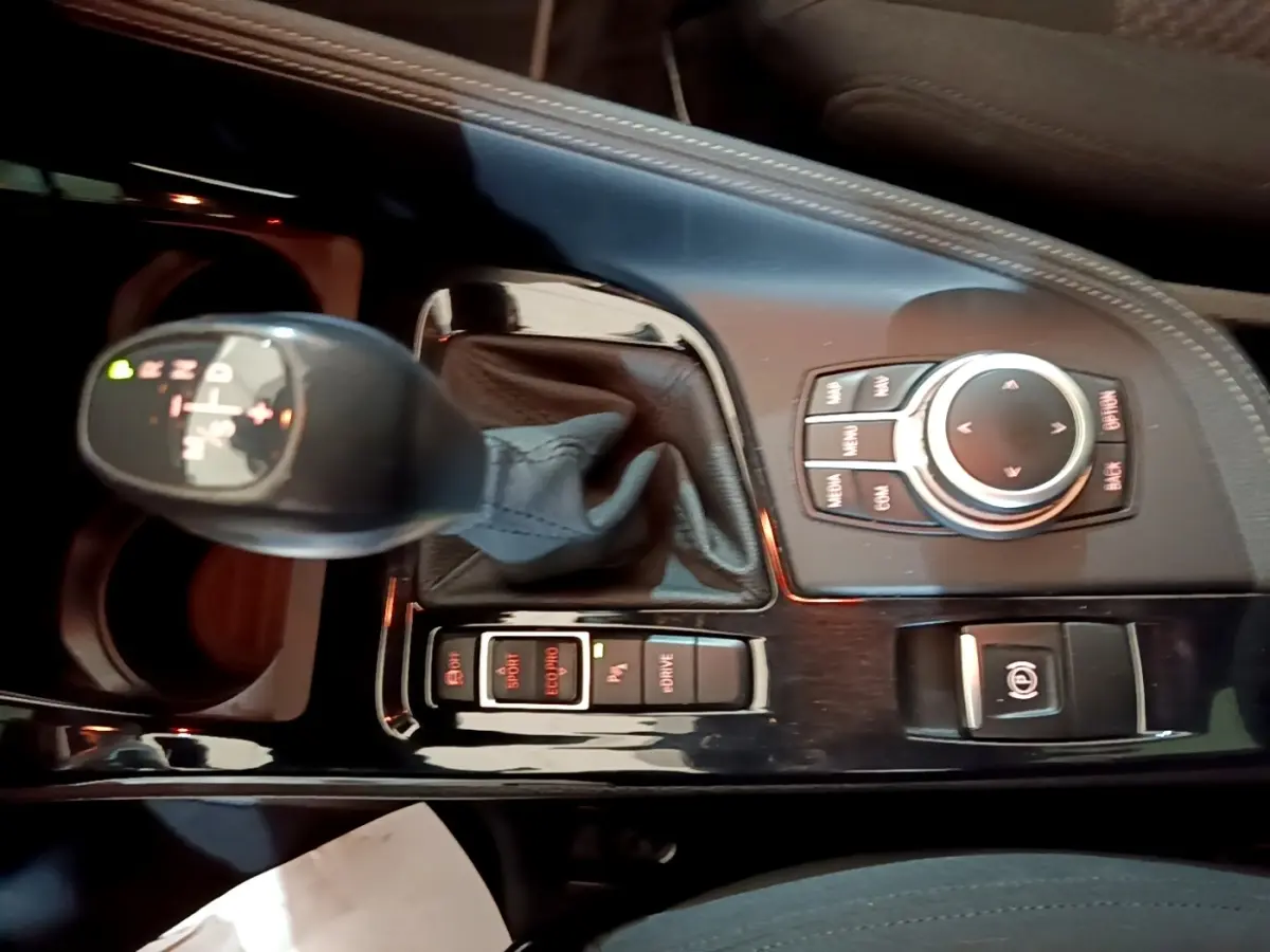 Vue rapprochée de la console centrale noire du BMW X2 xDrive25e 2020, avec levier de vitesse automatique et commandes multimédia.