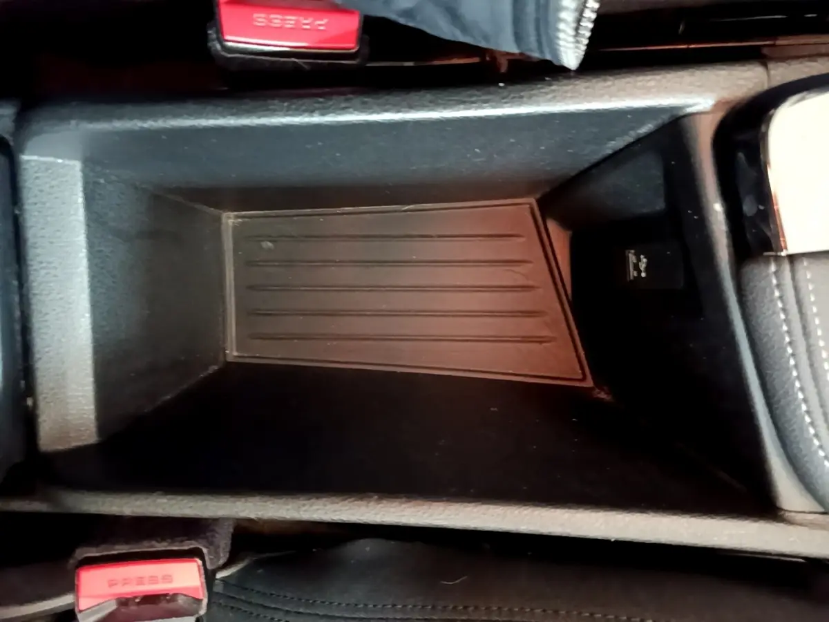 Gros plan sur le rangement central noir de la BMW X2 hybride rechargeable, avec bouton USB visible à droite.