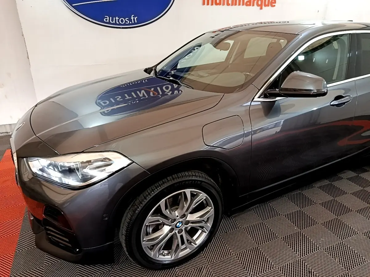 BMW X2 xDrive25e gris métallisé vue 3/4 avant droit, mettant en valeur les jantes alliage et les phares LED.