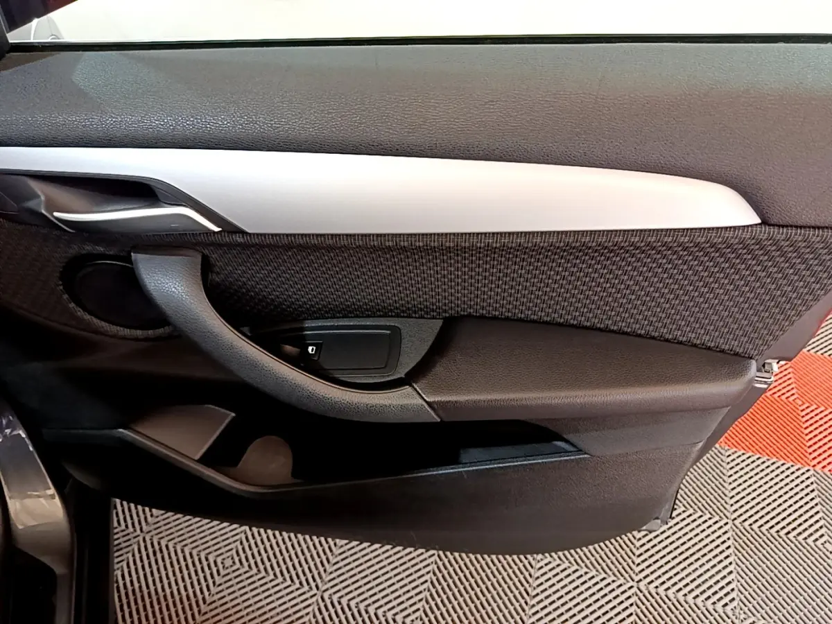 Vue intérieure côté gauche de la porte BMW X2 xDrive25e avec garniture noire et insert argenté.