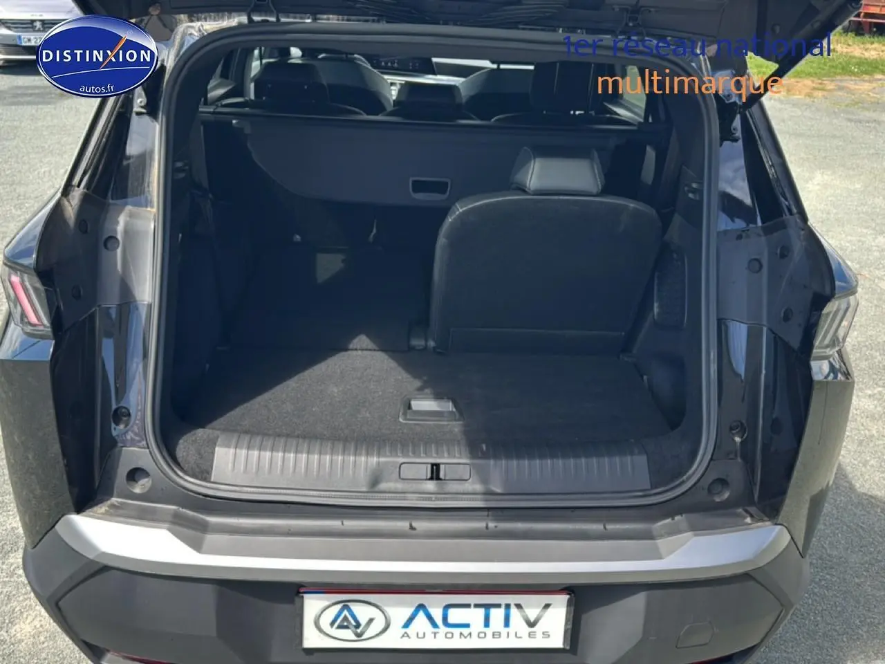 Coffre ouvert vue arrière d’un Peugeot 5008 noir avec banquette arrière partiellement rabattue.