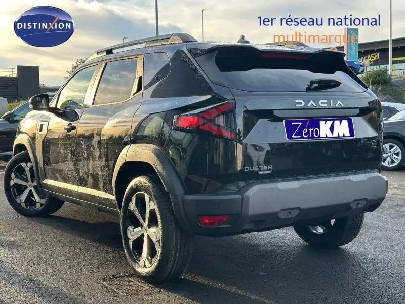 Vue 3/4 arrière droite du Dacia Duster 1.8 hybrid 155ch Journey noir nacré métallisé avec jantes distinctives.