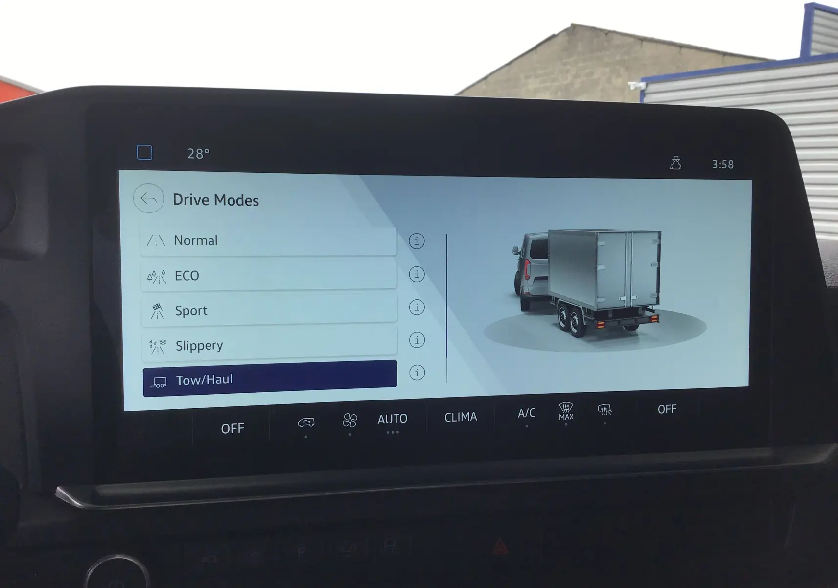 Écran tactile du Volkswagen Transporter T7 en mode conduite avec remorque, affichant les options de conduite et une animation arrière grise.