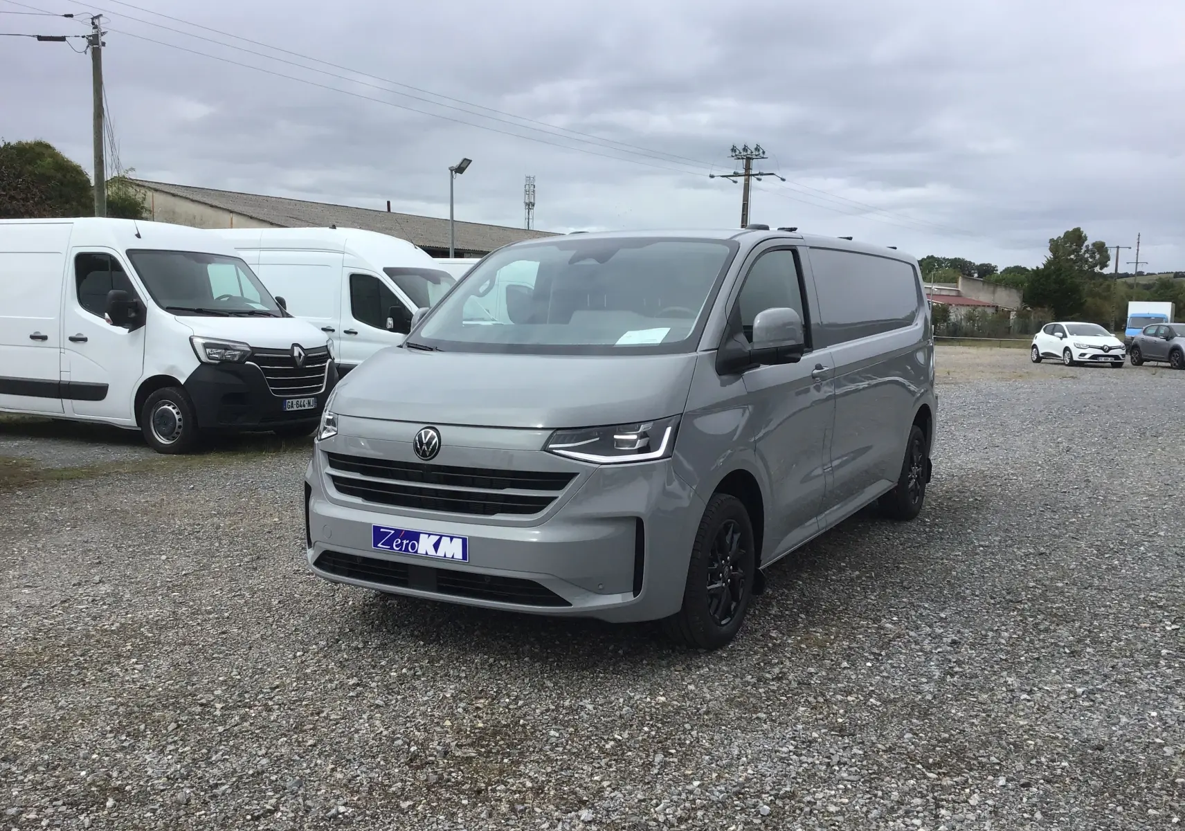 Volkswagen Transporter T7 gris Stone vu en 3/4 avant droit avec projecteurs LED Matrix et barres de toit repliables.