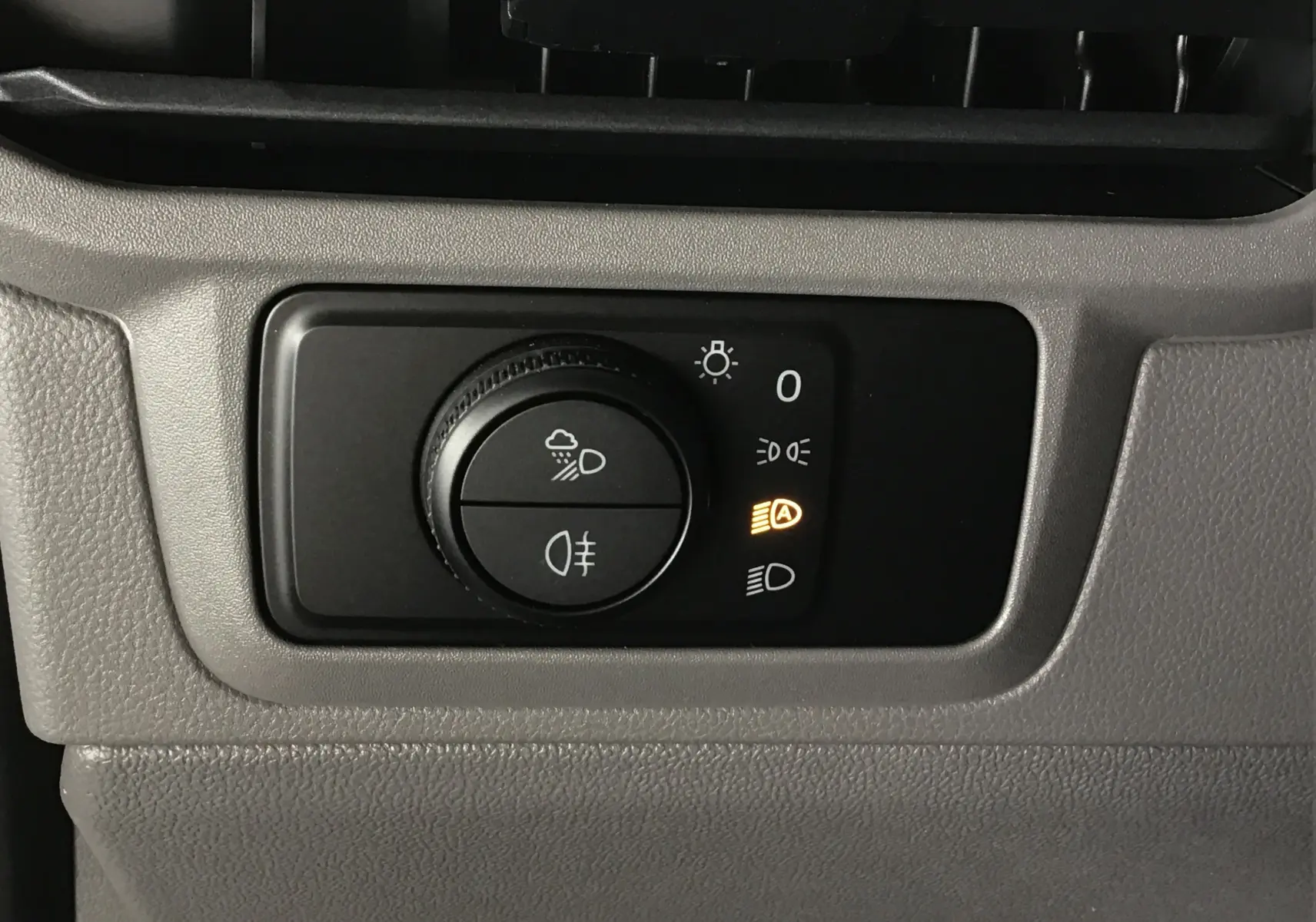 Gros plan sur la commande d'éclairage du Volkswagen Transporter T7 gris stone, avec témoin de feux automatiques allumé.