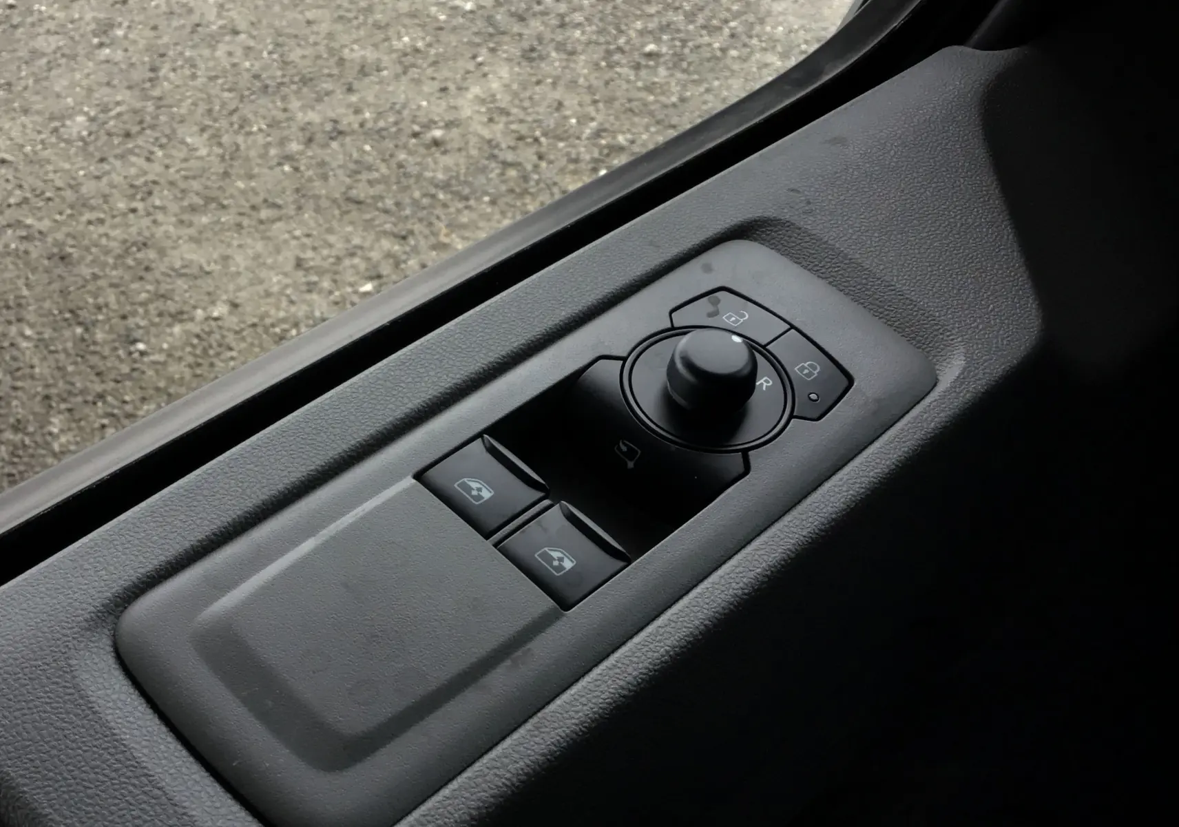 Commande des rétroviseurs et des vitres côté conducteur du Volkswagen Transporter T7 gris stone, vue en plongée.