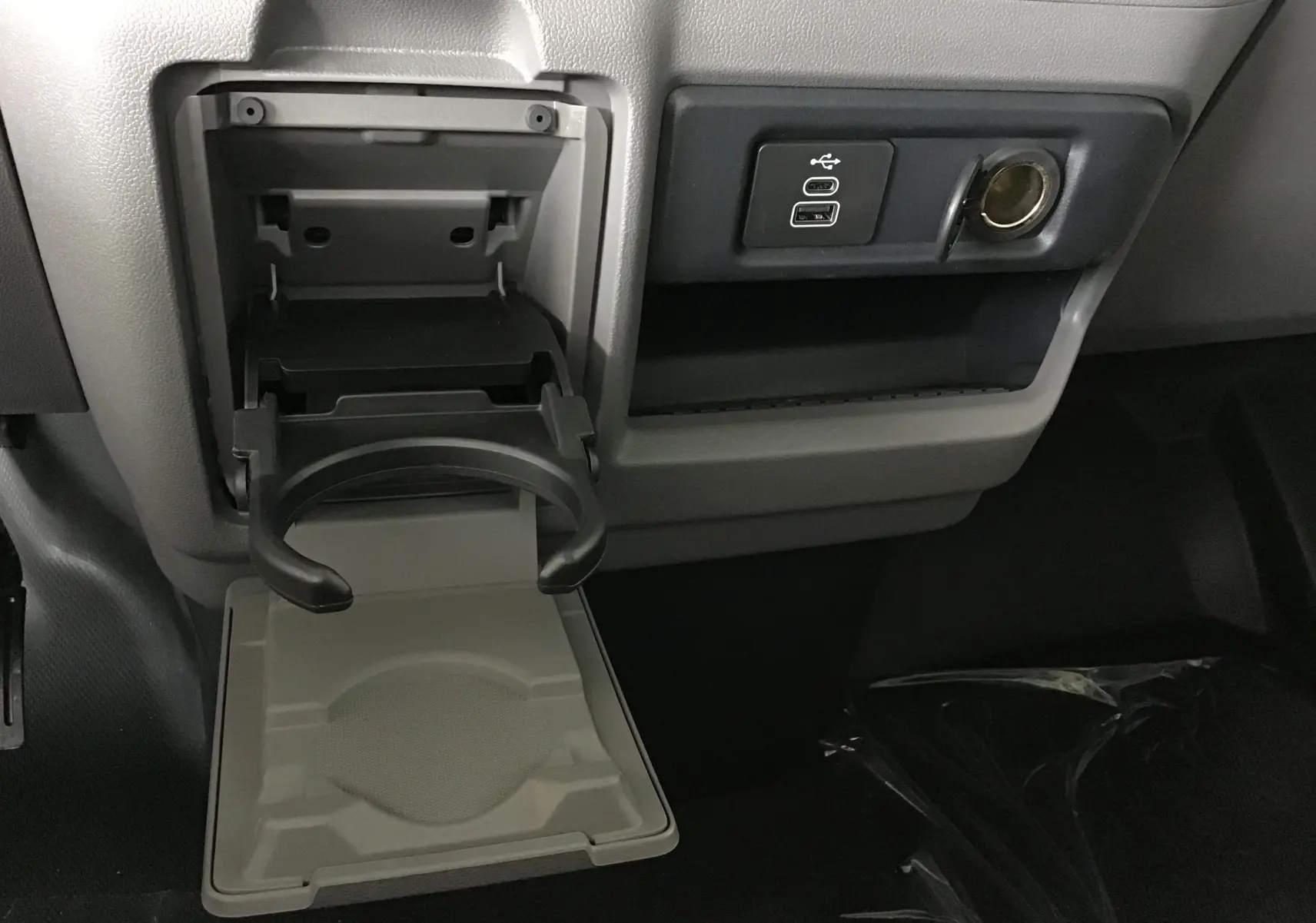 Gros plan sur le porte-gobelet déployé et les ports USB dans l'habitacle gris du Volkswagen Transporter T7.