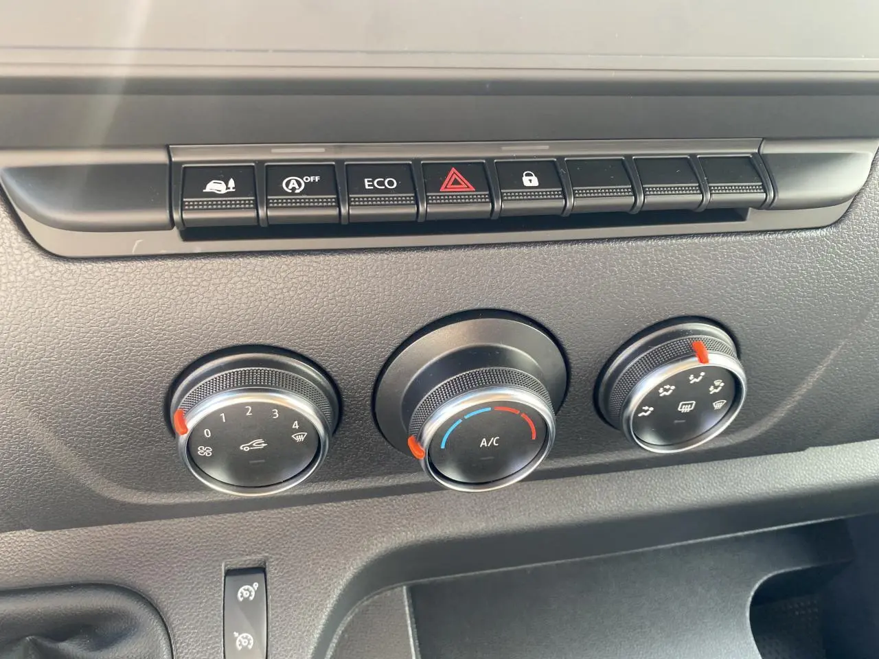 Gros plan sur les commandes de climatisation manuelle et boutons fonctionnels du tableau de bord du Nissan Interstar blanc.