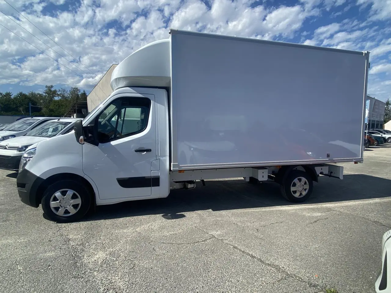 Profil droit d'un utilitaire blanc Nissan Interstar 2022 avec caisse grand volume et capucine sur parking.