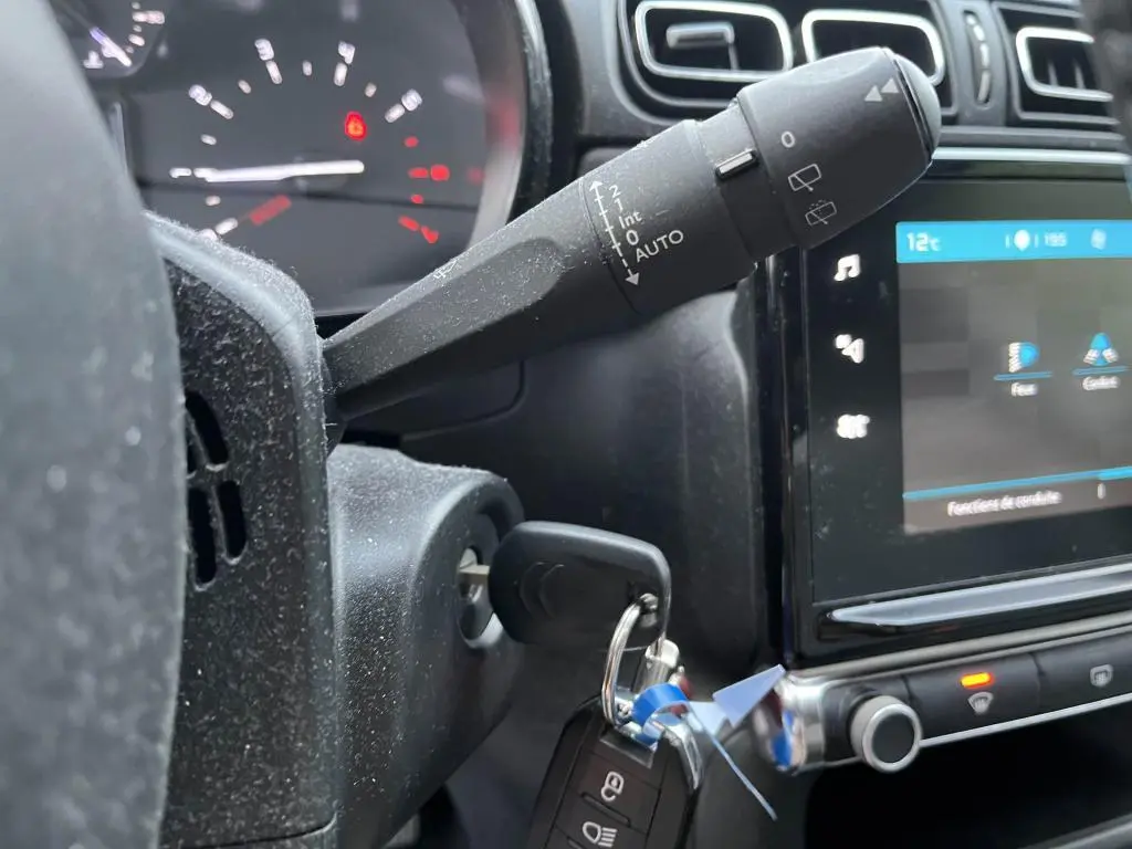 Gros plan sur la commande d'essuie-glace et le tableau de bord numérique d'une Citroën C3 gris foncé de 2019.