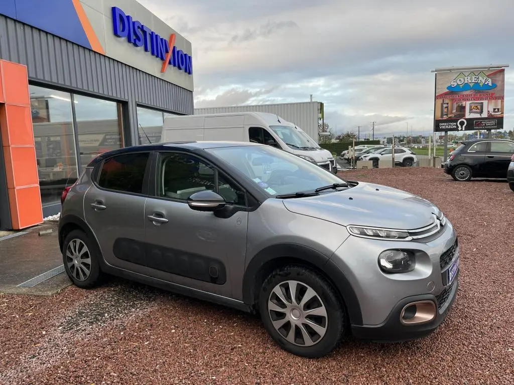 Citroën C3 gris foncé vue 3/4 avant droit avec protections latérales noires et coques de rétroviseurs noir brillant.