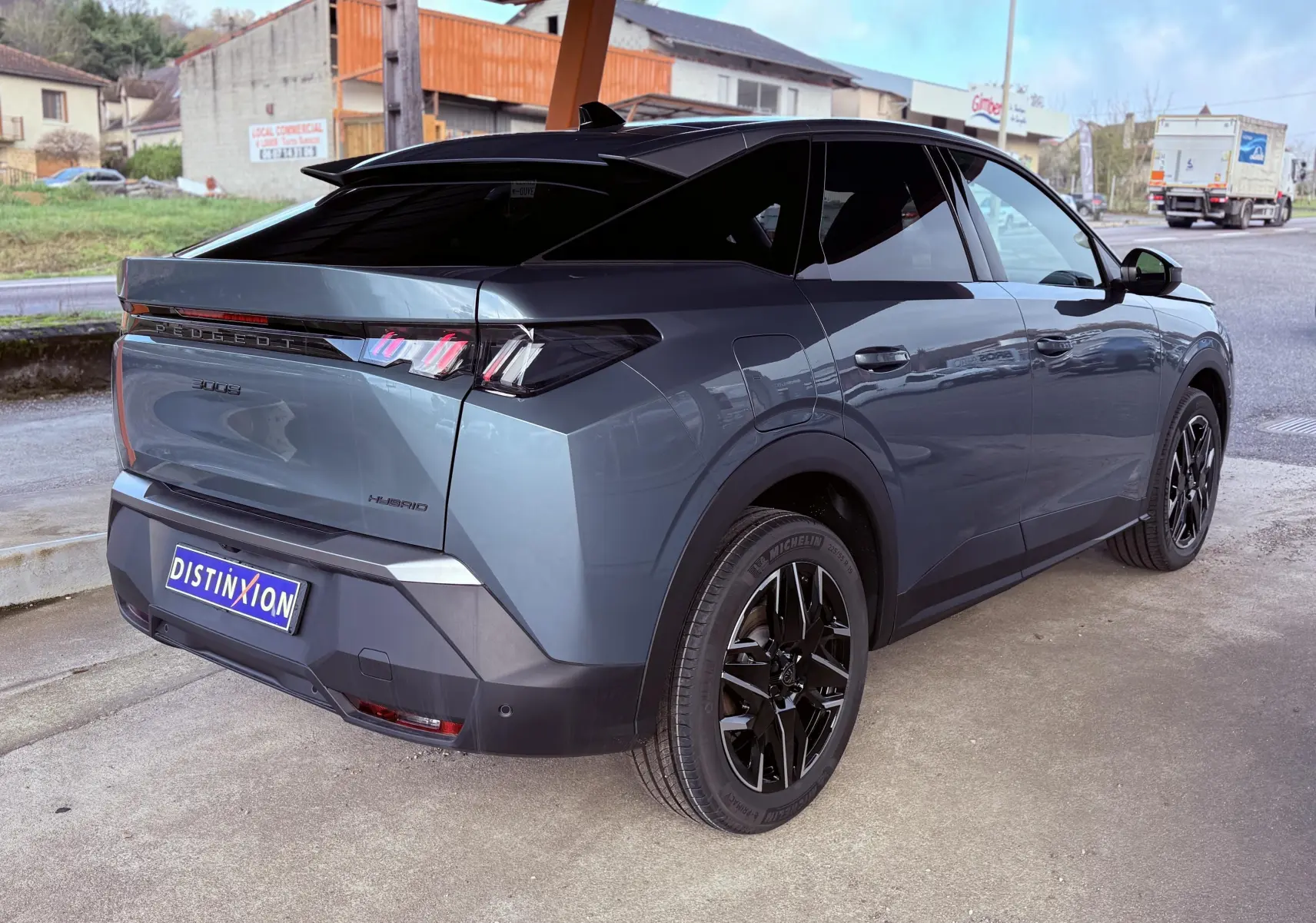 Vue 3/4 arrière droite du Peugeot 3008 Hybrid 136ch Allure en bleu Ingaro métal avec jantes noires et toit noir contrasté.