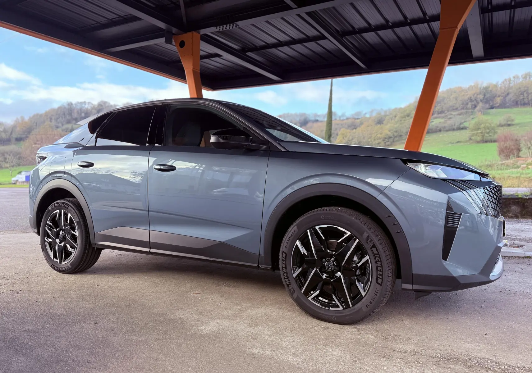 Peugeot 3008 Hybrid 136ch Allure bleu Ingaro métal en vue profil côté gauche sous abri avec jantes noires distinctives.