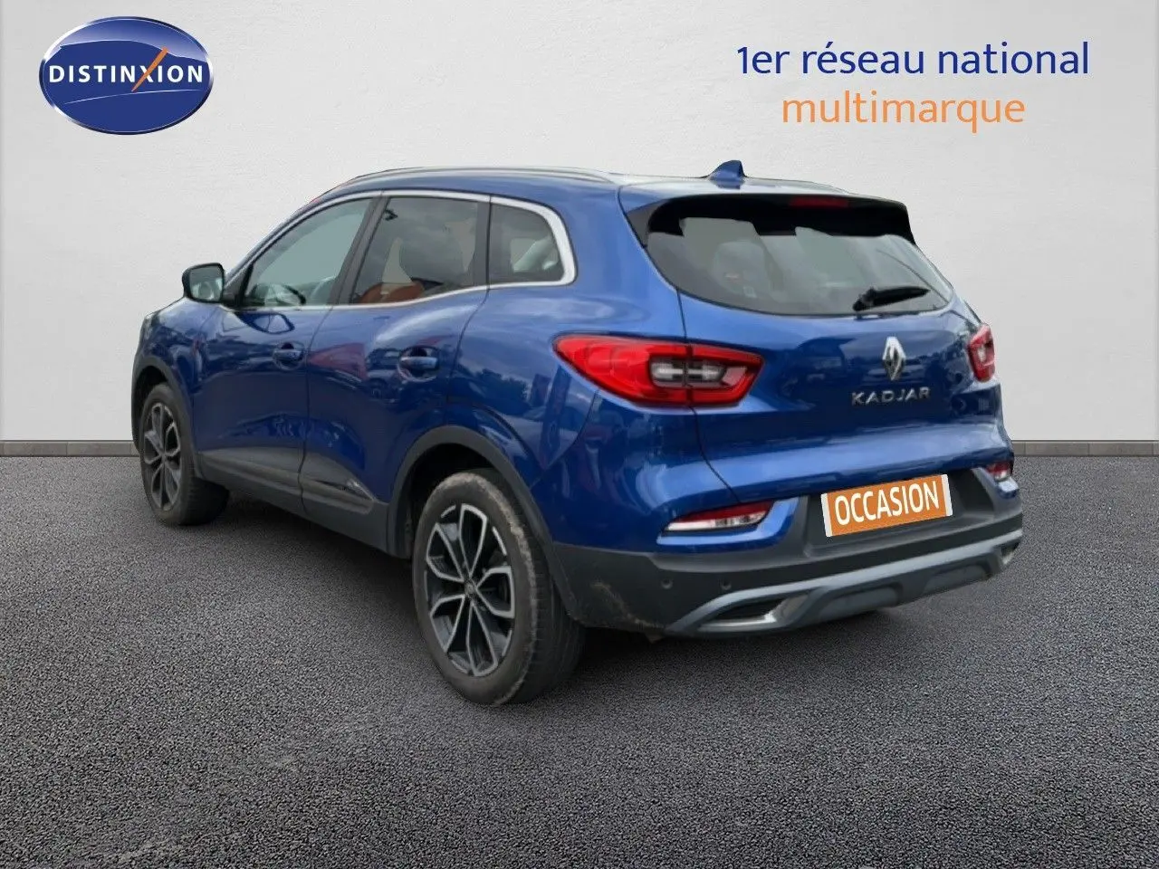 Vue 3/4 arrière droite du Renault Kadjar bleu Iron avec jantes alliage et logo visible sur un fond neutre.