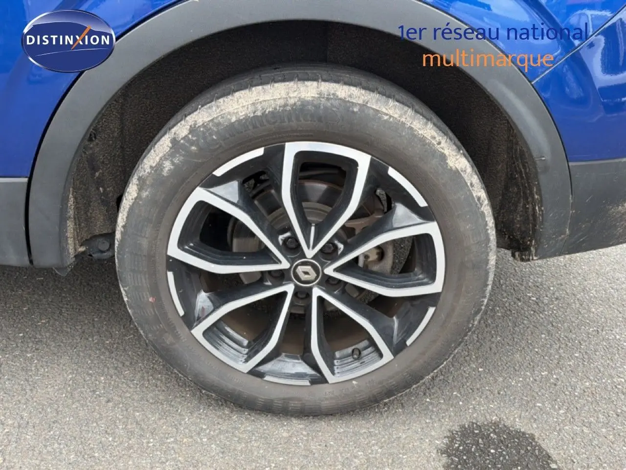 Gros plan sur la roue avant gauche du Renault Kadjar bleu Iron, mettant en valeur la jante alliage noire et argentée.