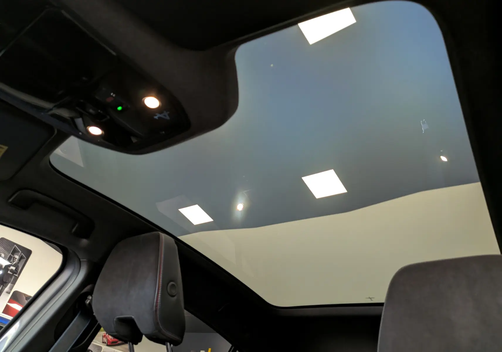Vue intérieure du toit panoramique en verre du Renault Rafale gris schiste, mettant en valeur l'éclairage et les sièges avant.