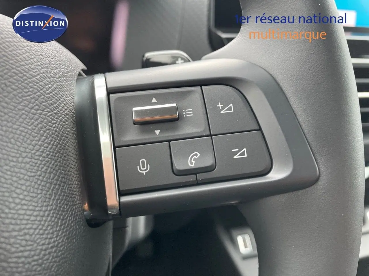 Gros plan sur les commandes vocales et téléphone intégrées au volant d'une Citroën C4 blanche 2024.