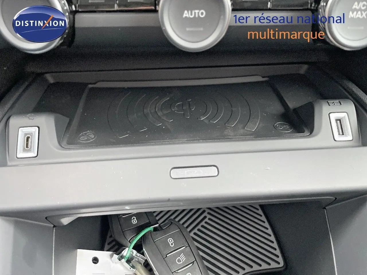 Gros plan sur la console centrale de la Citroën C4 blanche, montrant le chargeur sans fil et deux clés de voiture.