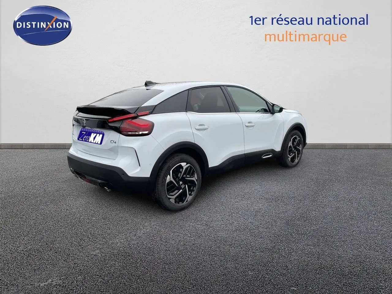 Citroën C4 blanc métal vue 3/4 arrière droit, avec toit noir et jantes bicolores distinctives.