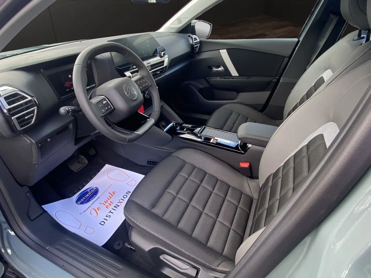 Intérieur avant droit de la Citroën C4 2025 Manhattan Green, sièges tissu noir et gris, tableau de bord moderne avec écran tactile.