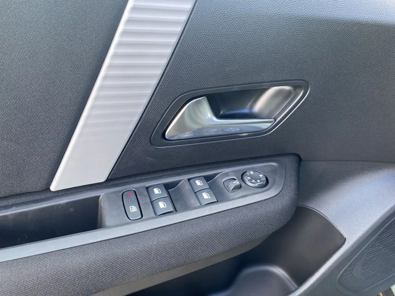 Détail de la porte côté gauche de la Citroën C4 Manhattan Green 2025 avec commandes de vitres et poignée argentée.