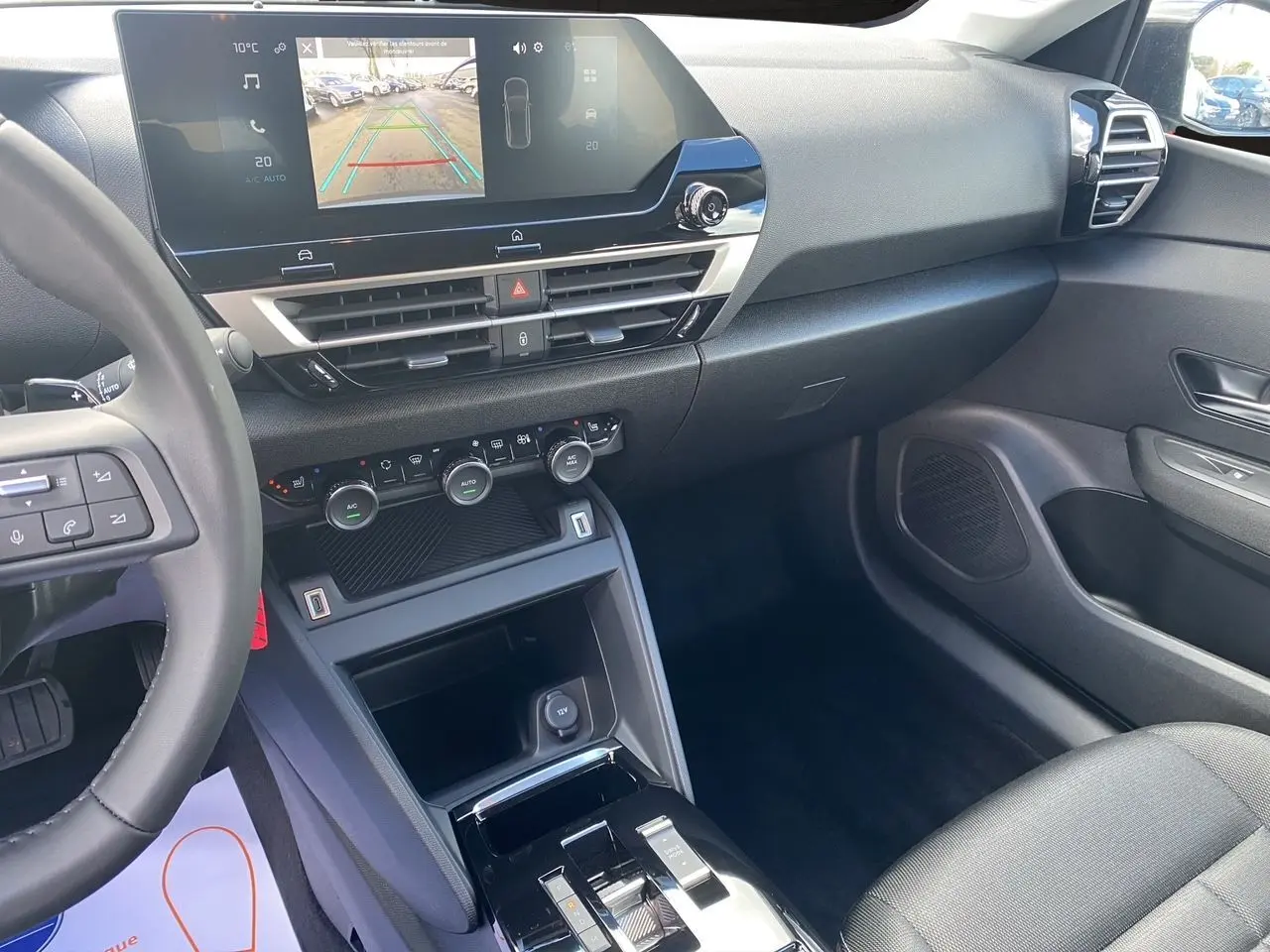 Intérieur avant droit de la Citroën C4 hybride 2025 avec tableau de bord noir et écran tactile 10 pouces en marche.