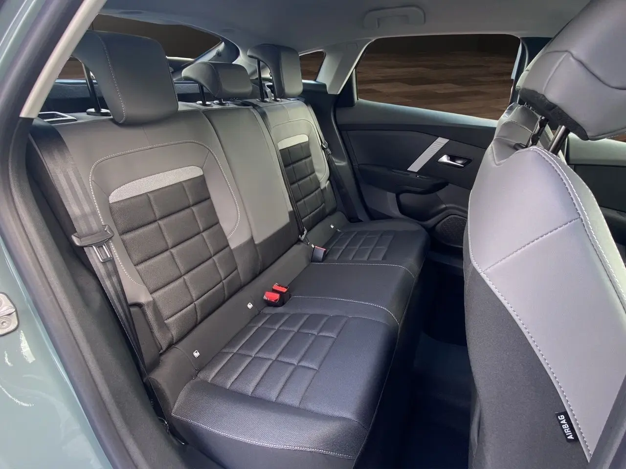 Vue intérieure arrière droite des sièges en tissu noir et gris de la Citroën C4 Nouvelle Plus Hybrid 2025 Manhattan Green.