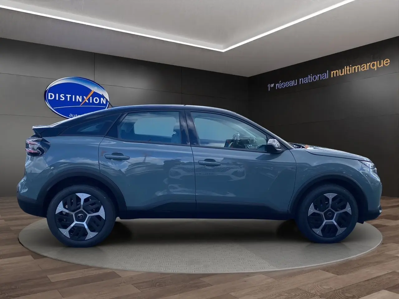 Profil droit de la Citroën C4 2025 Manhattan Green avec toit noir et jantes stylisées en showroom.