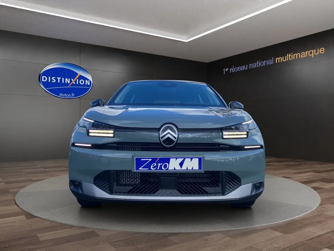 Vue avant d'une Citroën C4 2025 Manhattan Green avec feux LED et calandre noire dans un showroom.