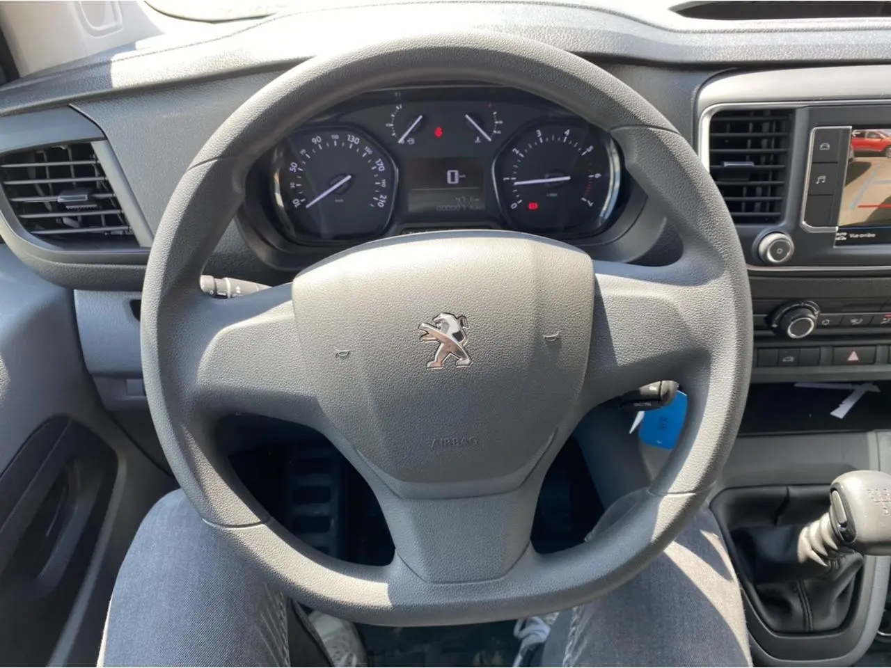 Vue intérieure centrée sur le volant Peugeot du Expert Fourgon gris platinium avec tableau de bord et levier de vitesse manuel.