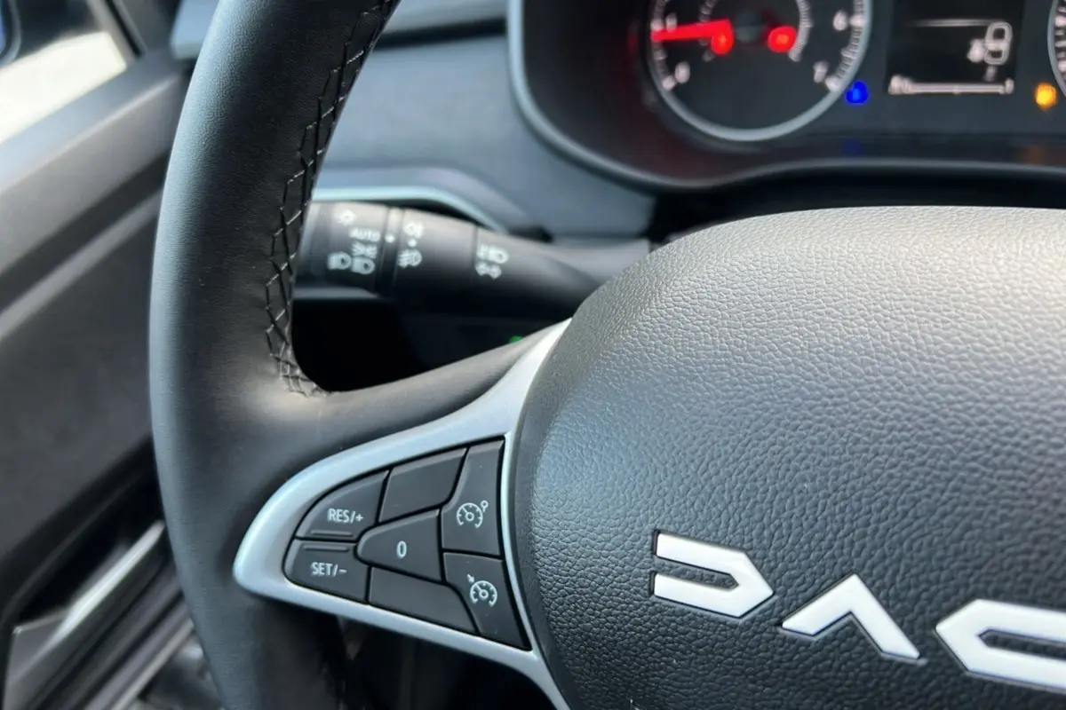 Gros plan sur le volant noir de la Dacia Sandero Stepway 2024, avec commandes de régulateur de vitesse visibles.
