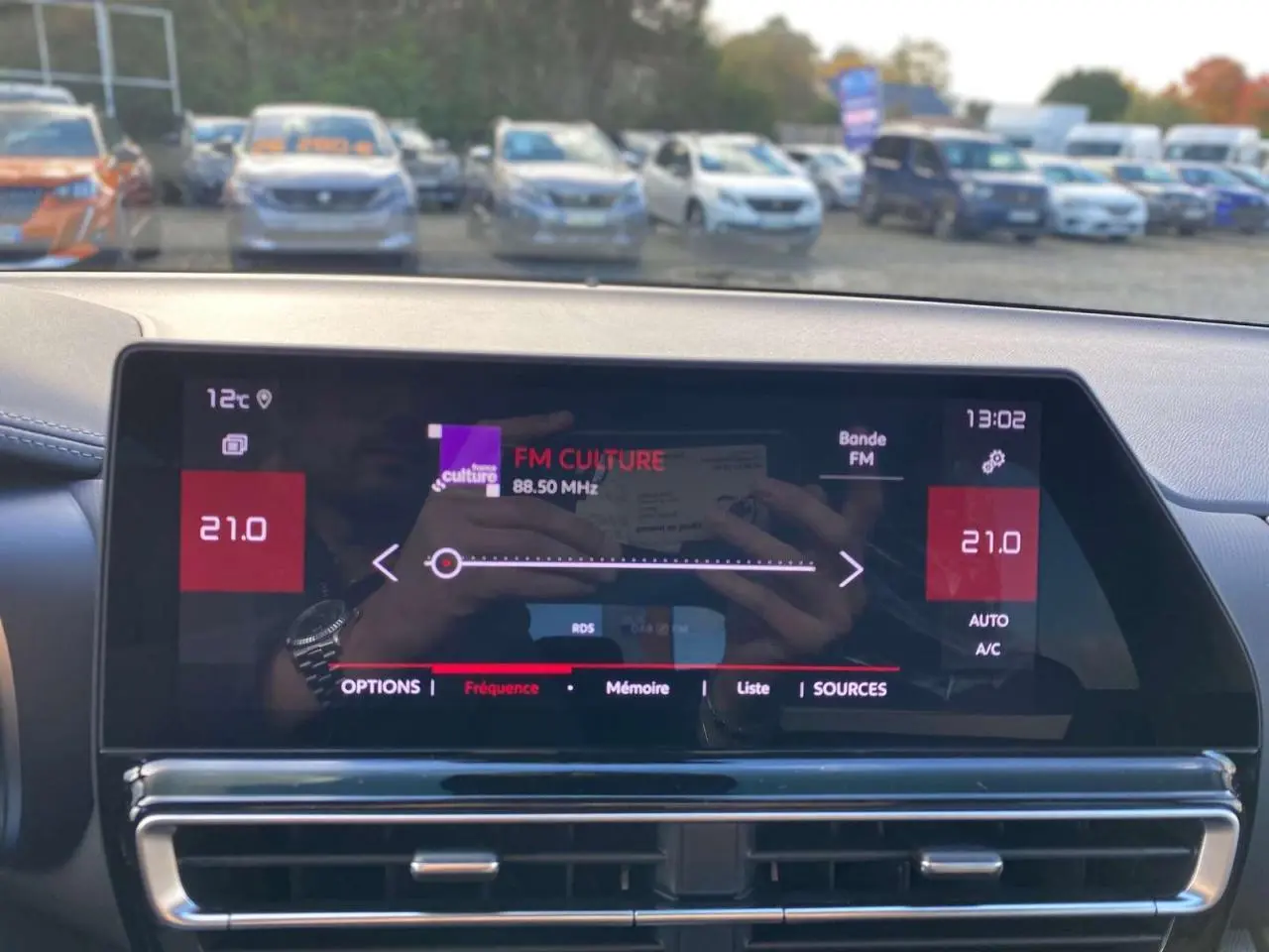 Écran tactile central du tableau de bord du Citroën C5 Aircross 2025 affichant la radio FM et la climatisation à 21°C.