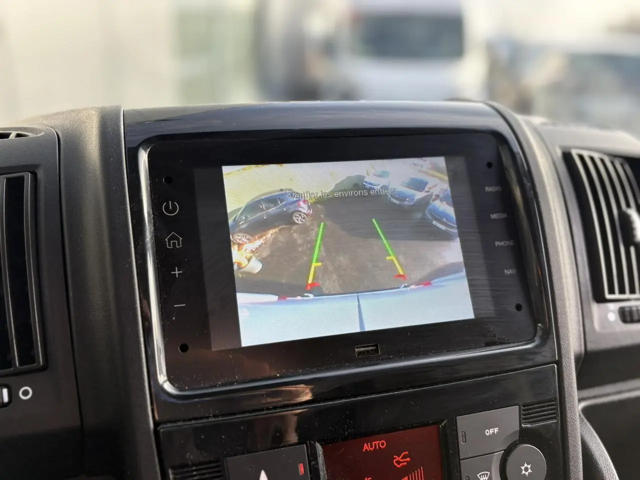 Écran de caméra de recul affichant l'arrière du fourgon blanc Opel Movano 2024 avec lignes de guidage colorées.