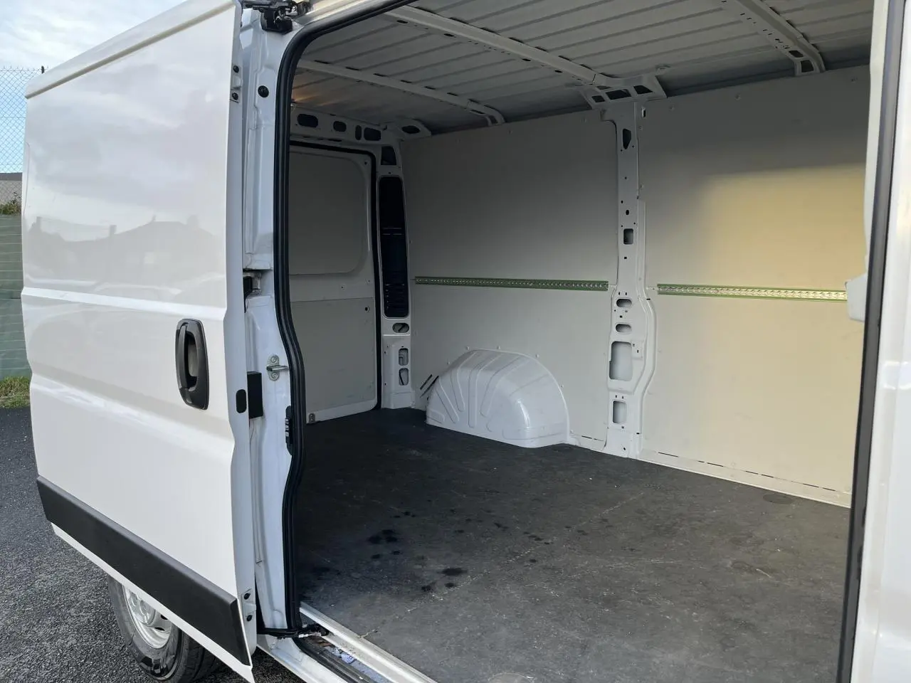 Vue intérieure côté droit du fourgon blanc Opel Movano 2024, porte latérale coulissante ouverte montrant l’espace de chargement vide.