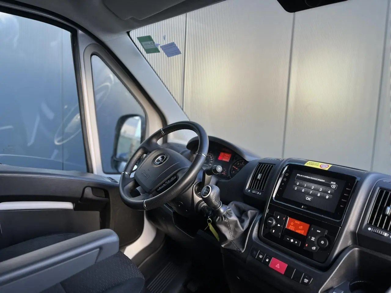 Vue intérieure côté conducteur de l’Opel Movano Fourgon blanc 2024, avec tableau de bord et écran tactile visible.