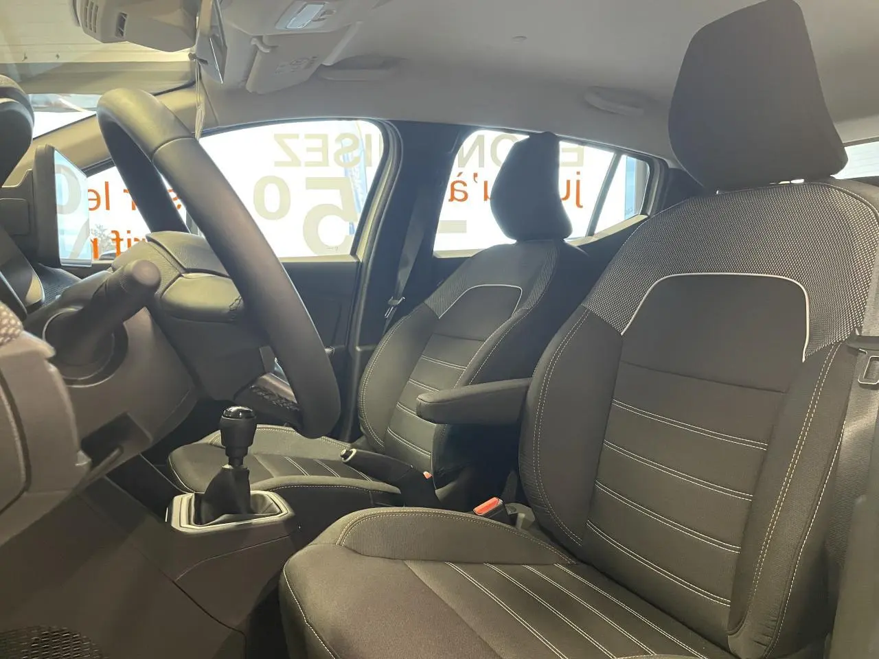 Vue intérieure de profil droit du Dacia Sandero TCe 90 Stepway Expression 2025, montrant les sièges noirs et la boîte manuelle.