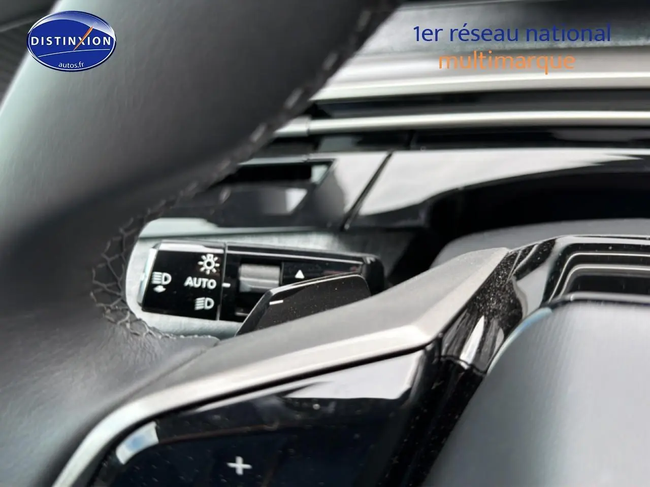 Gros plan sur le volant cuir noir et la commande des phares automatiques du Peugeot 5008 Hybrid 145 allure e-dcs6.