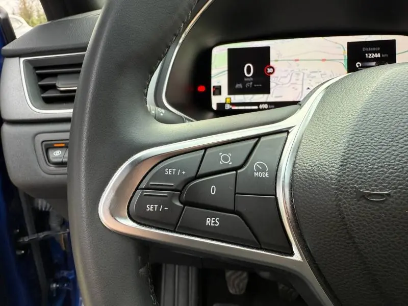 Gros plan sur le volant côté gauche du Renault Captur 2025 Bleu Iron/Noir Étoilé avec commandes de régulateur et tableau de bord numérique.